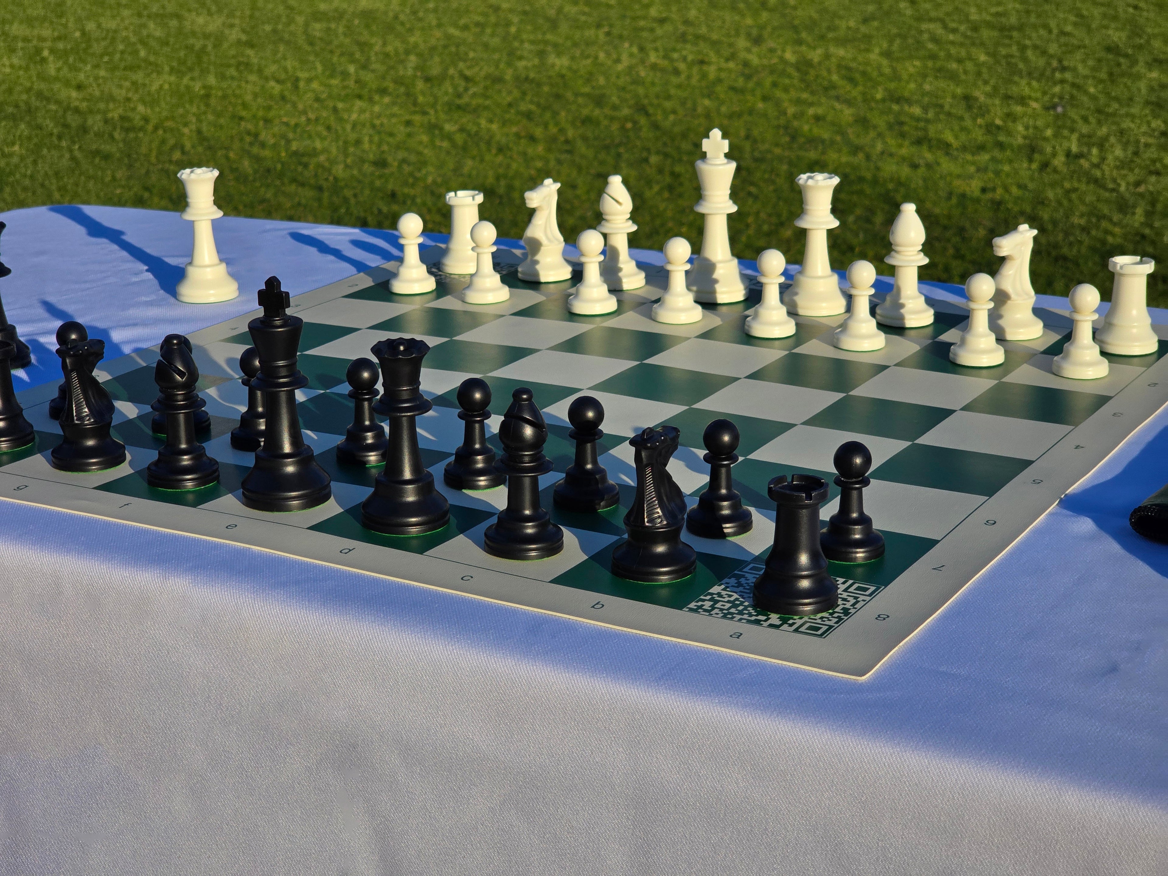 ChessKid Tote Chess Set with Vinyl Chess Board on White Table Cloth in Park