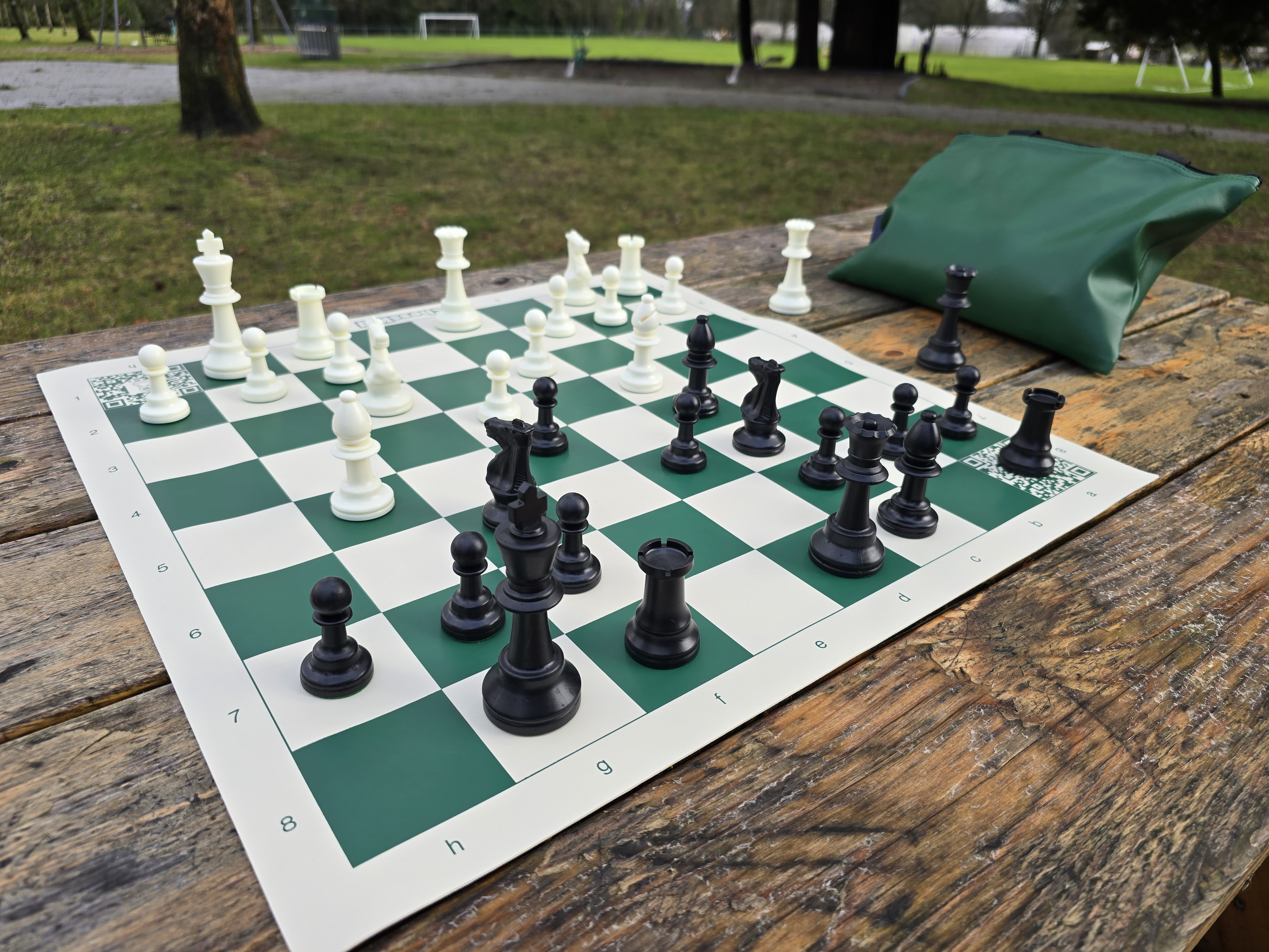 ChessKid Tote Chess Set with Vinyl Chess Board on Park Bench (Angled Shot from Black&