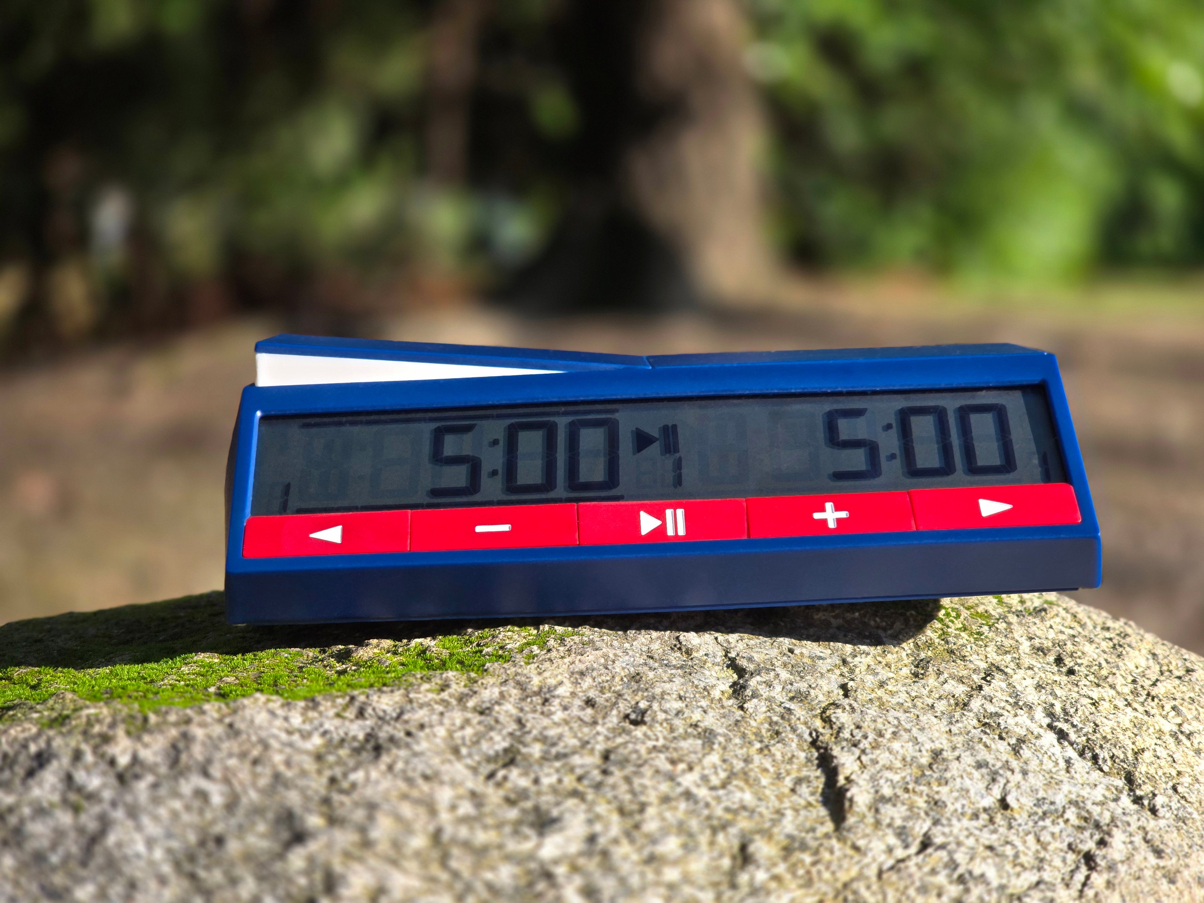 DGT North American Chess Clock 2024 on Rock Outside with Blurred Forest Background