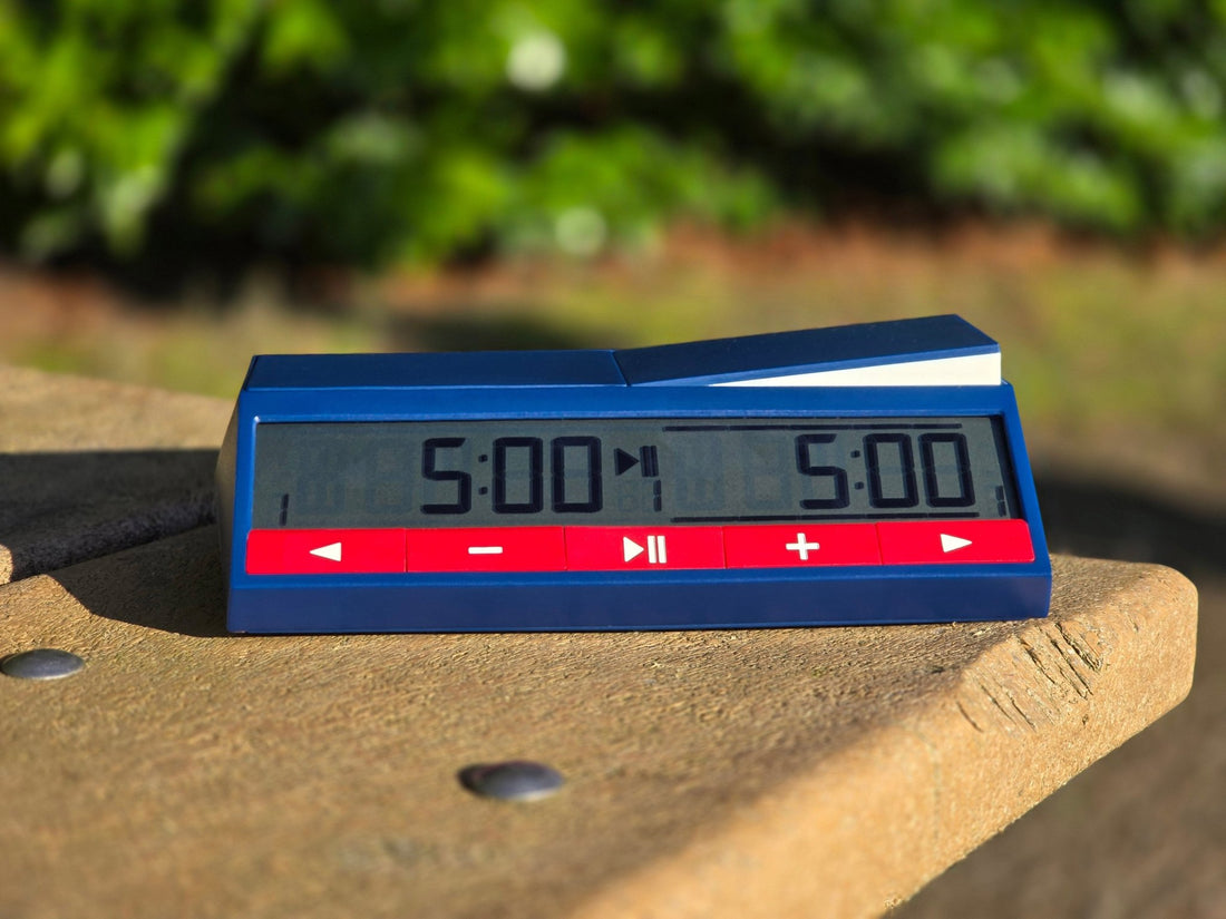 DGT North American Chess Clock 2024 on Park Bench Outside with Blurred Forest Background