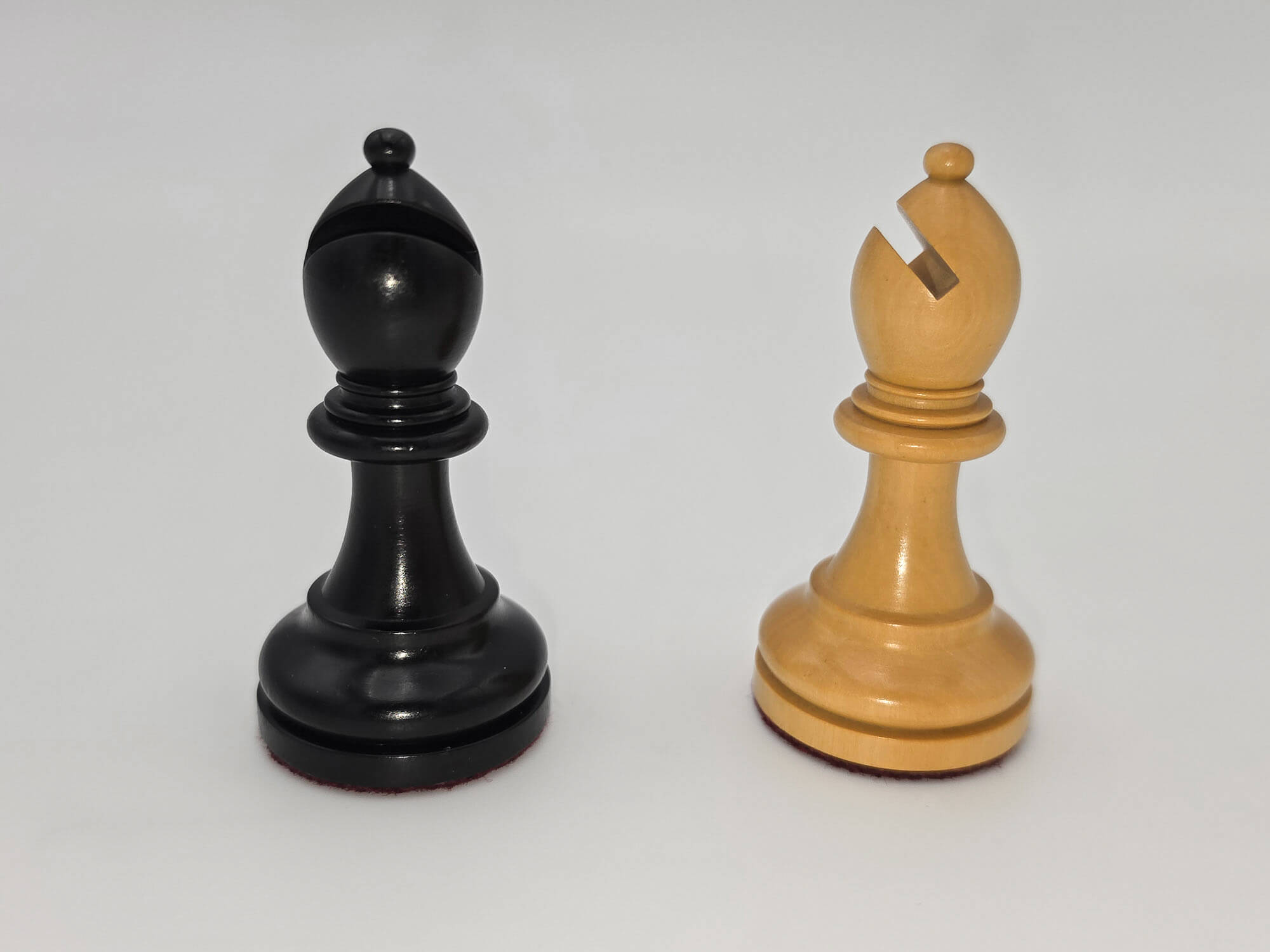 Black and natural wood Judit Polgar chess set bishops standing side by side against a white background.