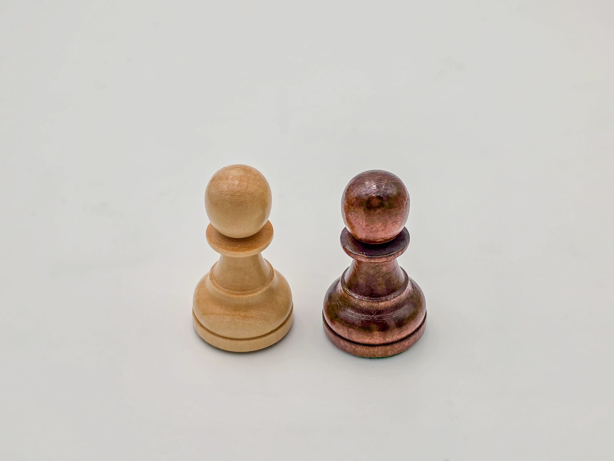 Macro shot of the light and dark Germanic-style wooden chess pawns from the Monarch Series, showing the polished finish and handcrafted wood grain.