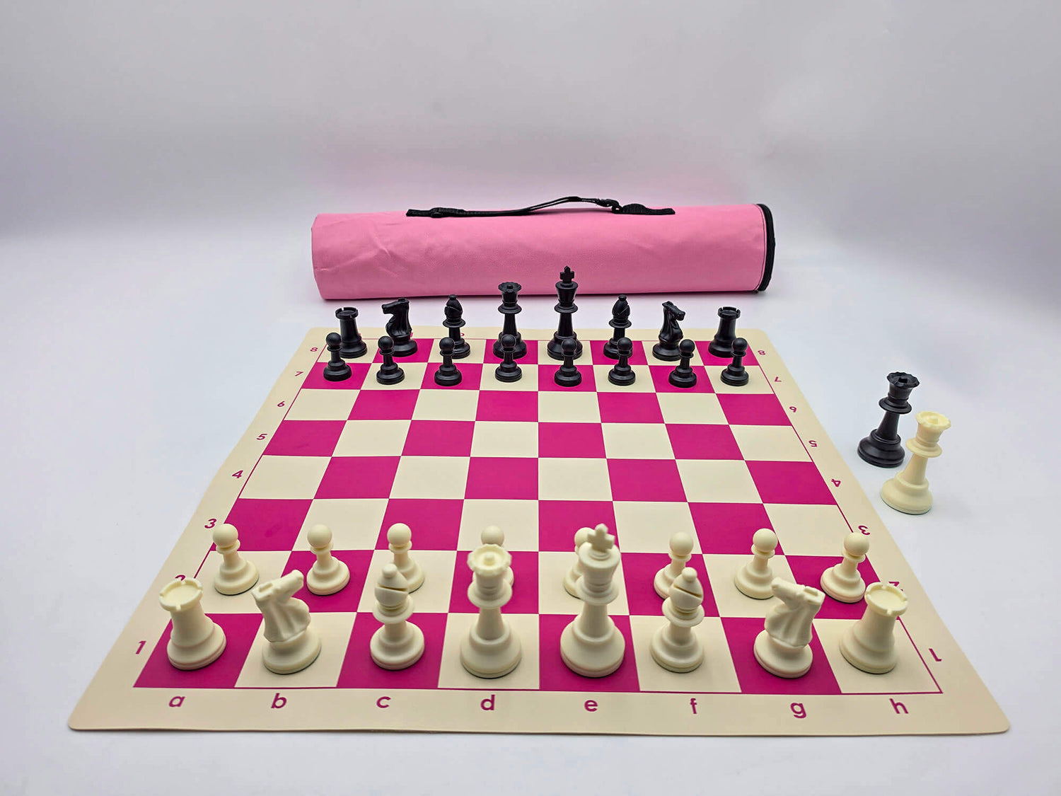 Pink quiver chess set with black and white Staunton pieces set up on a pink and white vinyl board in front of a matching pink bag.