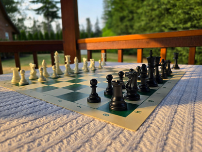 Tournament Chess Set on a Vinyl Chess Board on a White Knit Tablecloth in a Gazebo Against a Lush Green Background