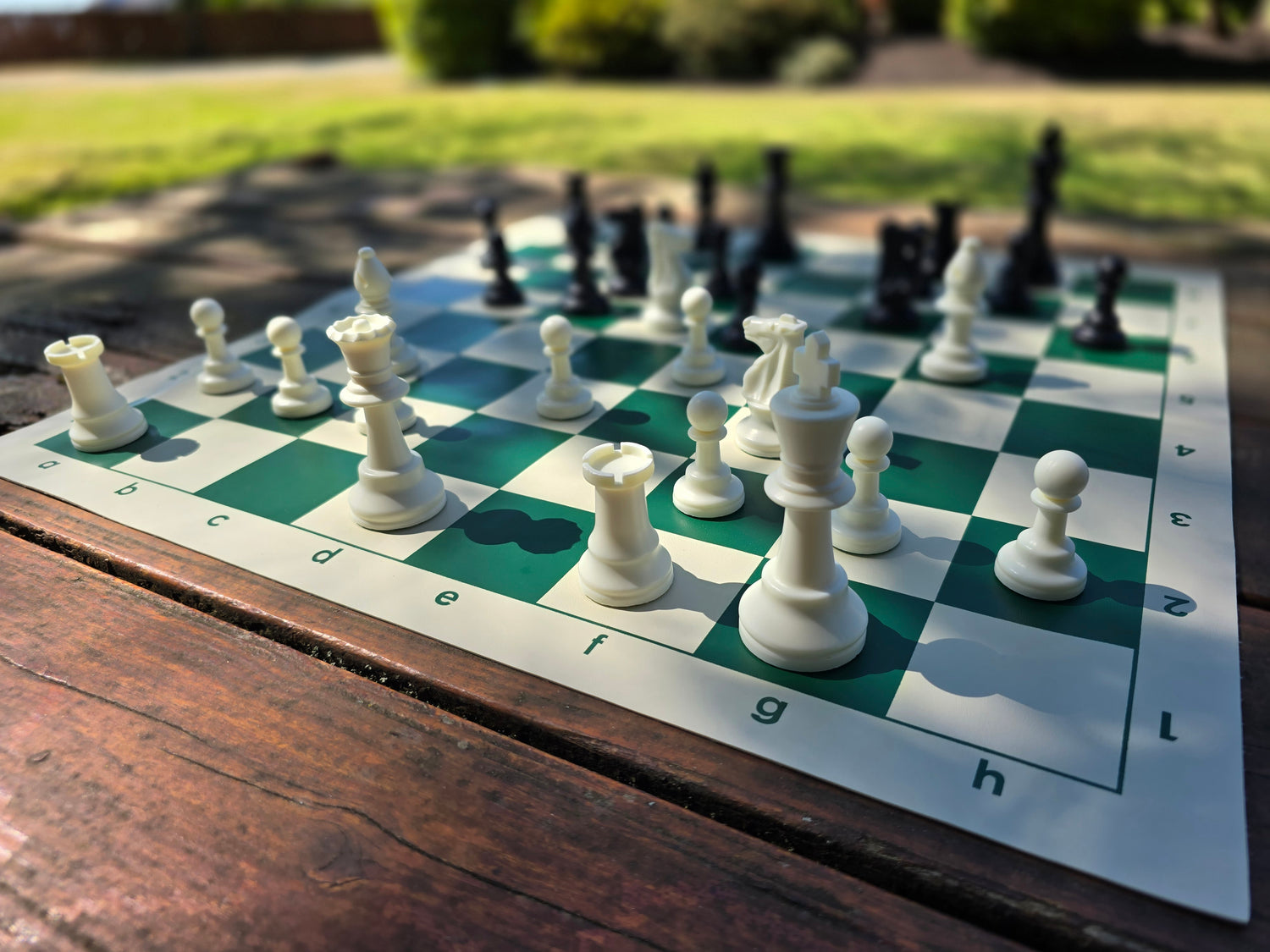Tournament Chess Set on a Vinyl Chess Board Outdoors on a Wooden Park Bench