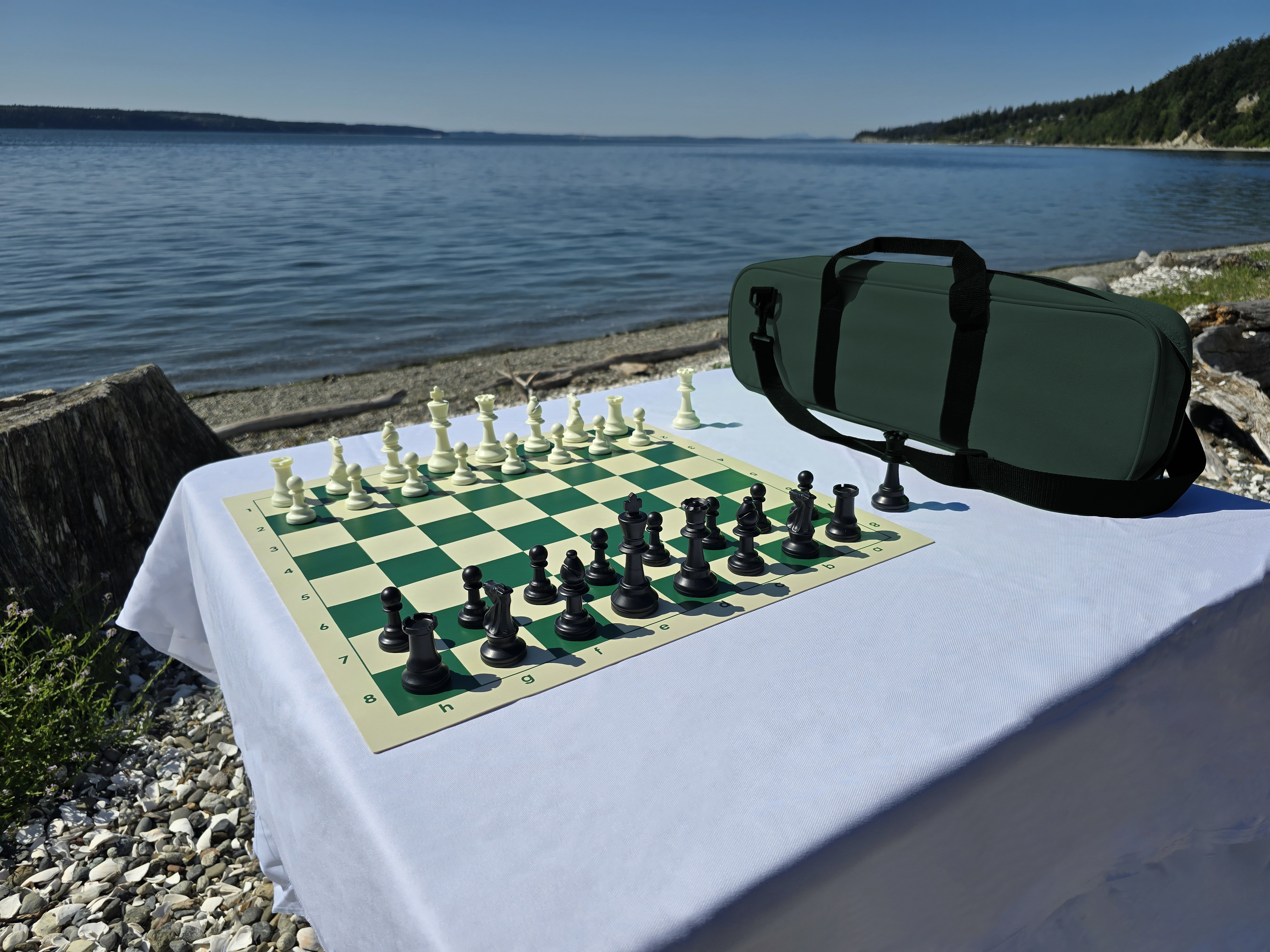 Tournament Chess Set on a Vinyl Chess Board with Deluxe Carrying Bag on a White Cloth Table on the Beach