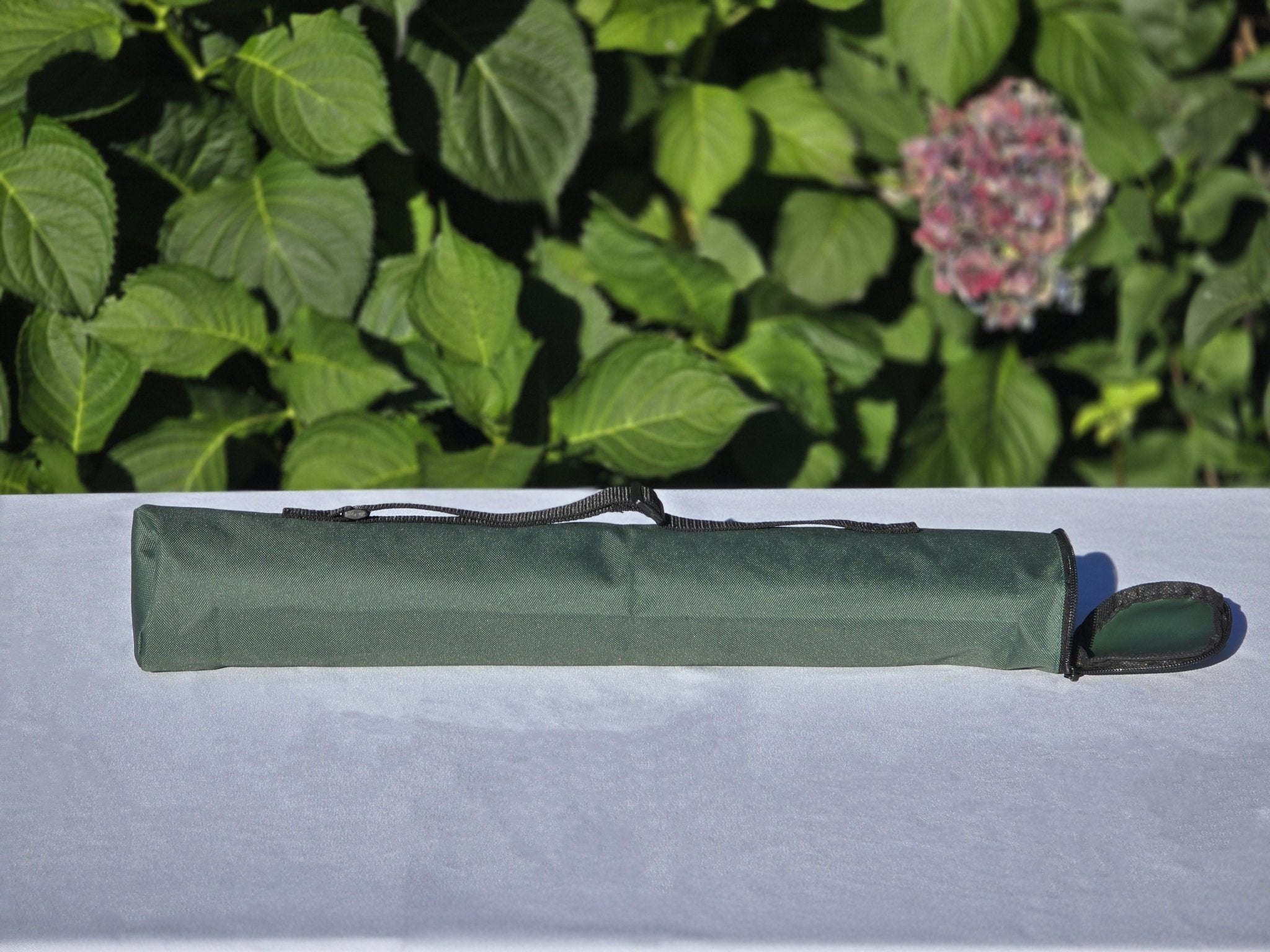 Quiver Carrying Bag on a White Cloth Table Against a Rose Bush Background (Side Shot)