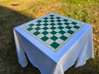 US Chess Federation Vinyl Chess Board on a White Cloth Table in a Sunlit Grass Field