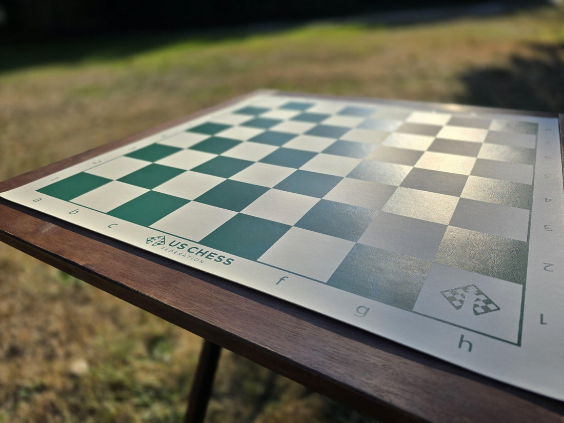 US Chess Federation Vinyl Chess Board on a Patio Table with in a Grassy Field with a Blurred Background