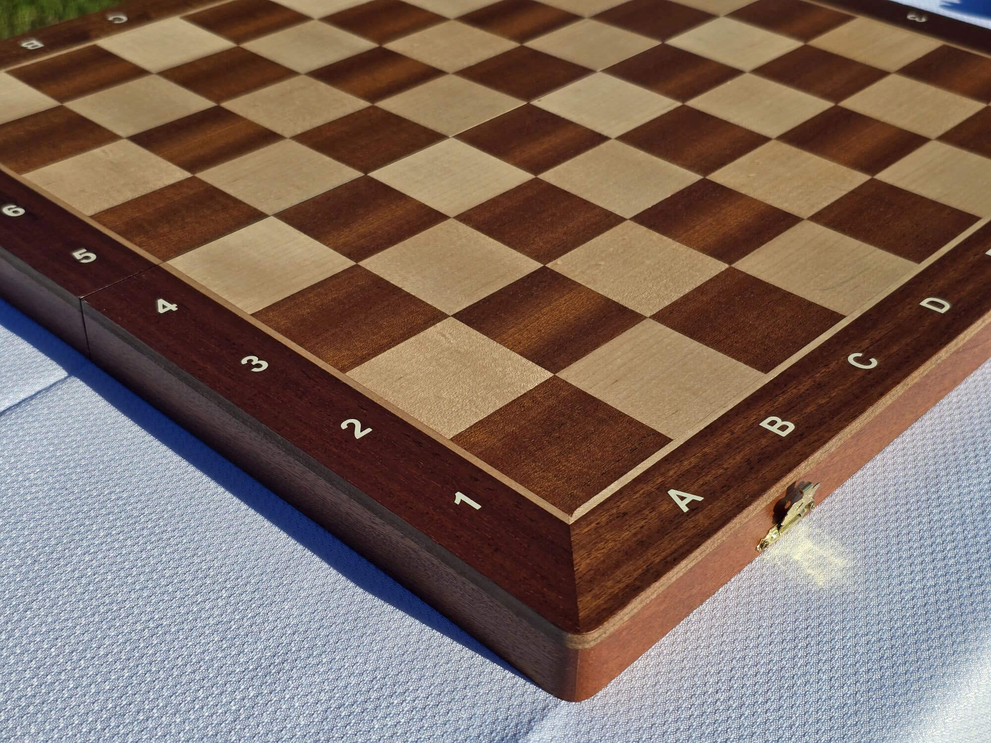 High-angle side view of the empty Aristocrat folding wooden chess board showcasing the alphanumeric coordinates and grain.