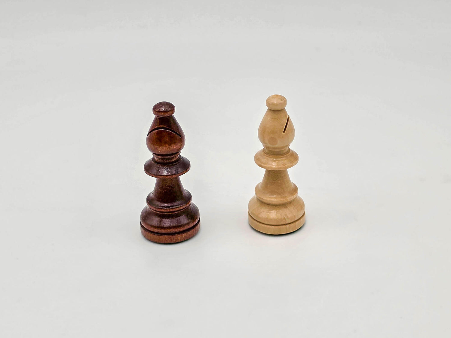 Detailed studio shot comparing the dark and light wooden bishop pieces from the Aristocrat chess set.