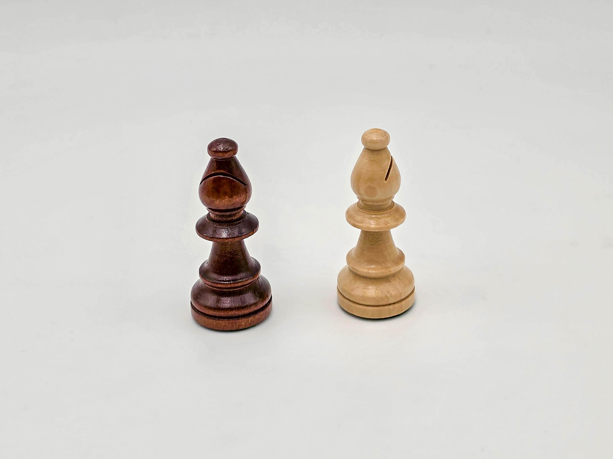 Detailed studio shot comparing the dark and light wooden bishop pieces from the Aristocrat chess set.