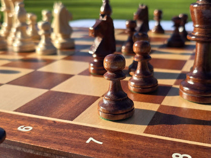 Close-up view of a dark wooden pawn and pieces on the Aristocrat folding board during a game setup.