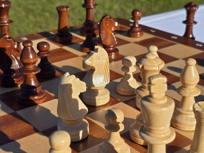 Detailed angle of the intricately carved dark and light wooden chess pieces arranged on the board.