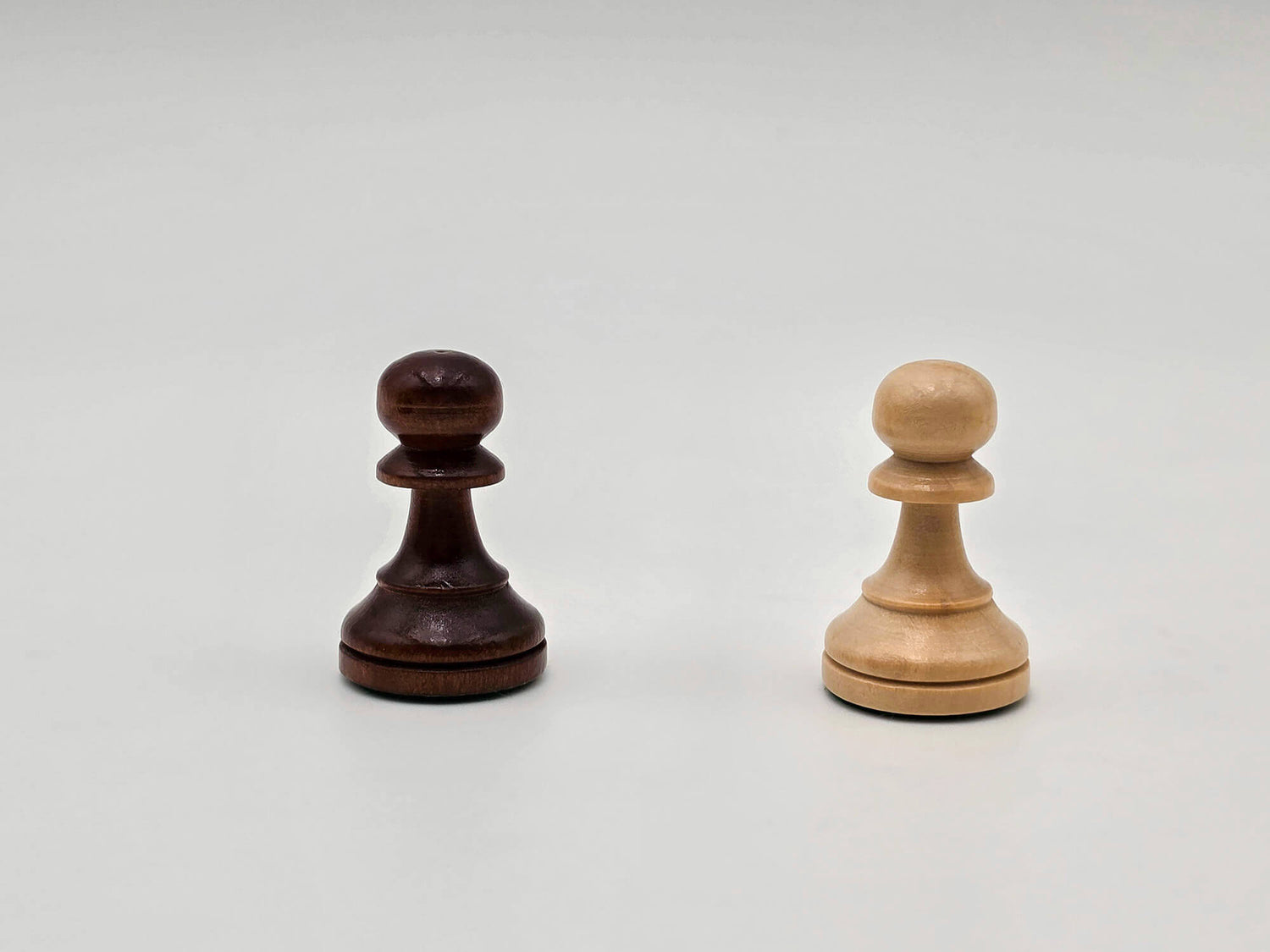 White background studio shot of the dark and light wooden pawn pieces from the Aristocrat chess set.