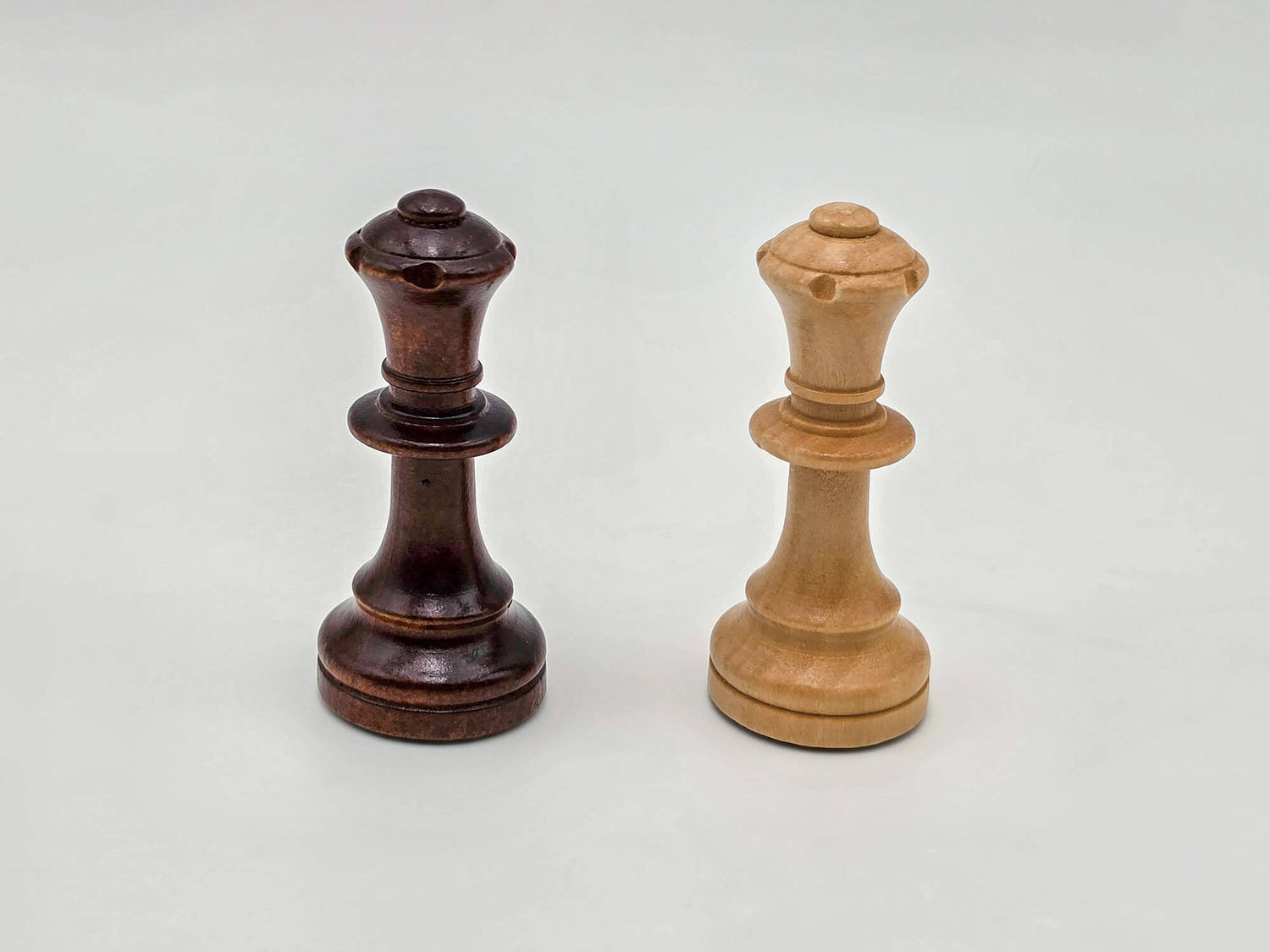 Studio product shot showing the elegant details of the dark and light wooden queen pieces from the Aristocrat set.