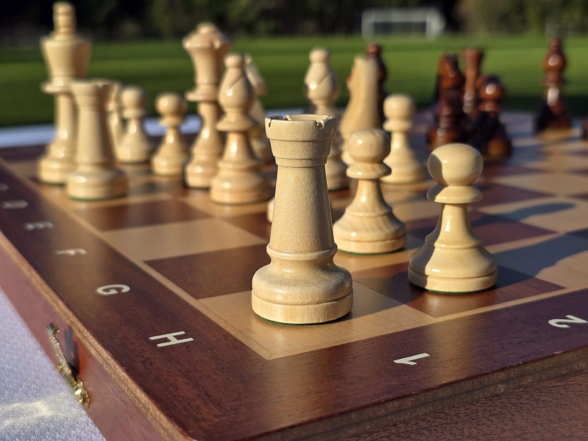 Macro view focusing on the finely carved white wooden rook and pawns of the Aristocrat chess set.