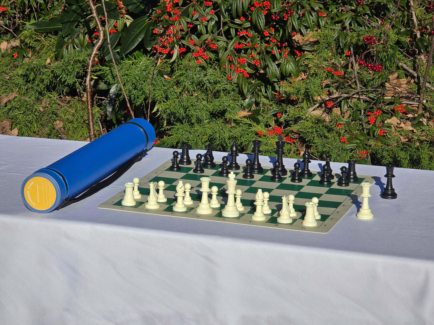 Blue Sentry telescopic chess tube with a roll-up vinyl board and Staunton pieces on a white tablecloth.