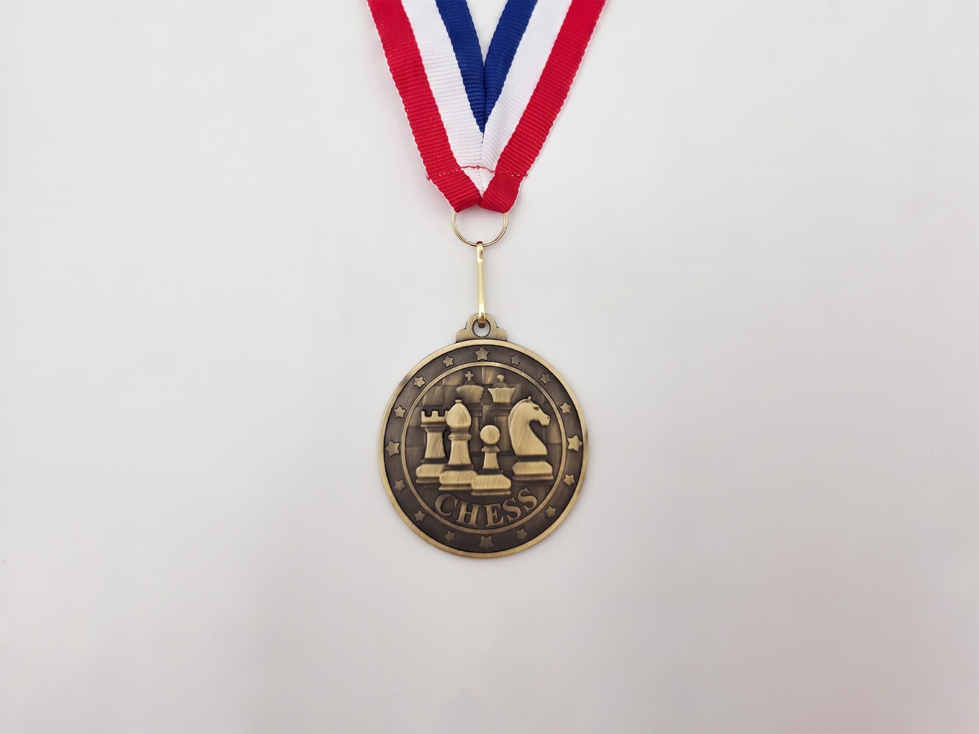 Classic Emblem gold chess medal featuring a 3D emblem with chess pieces on a red, white, and blue neck ribbon.