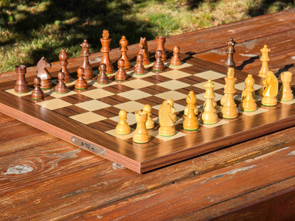 Overhead wide shot of the full DGT Timeless electronic chess pieces on a walnut USB-C wooden e-board displayed on a wooden table outdoors with a nature background.
