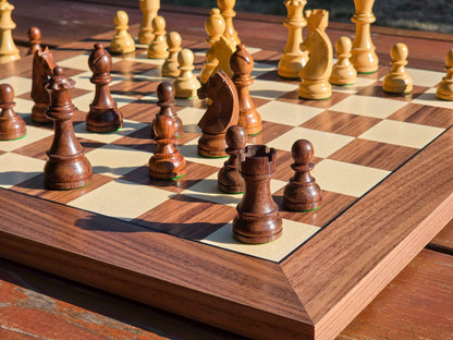 Low-angle close-up view focusing on the dark pieces of the DGT Timeless electronic chess set on a DGT Walnut e-board outdoors with a nature background.