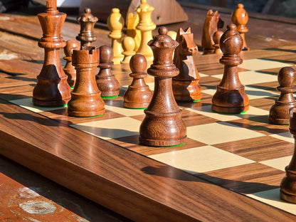Close-up perspective focusing on the Queen side and major pieces of the DGT Timeless set on a light and dark wooden board with a nature background.