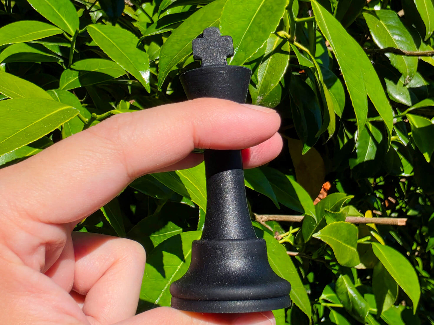 Demonstration of a flexible black silicone chess king piece being squeezed in hand.