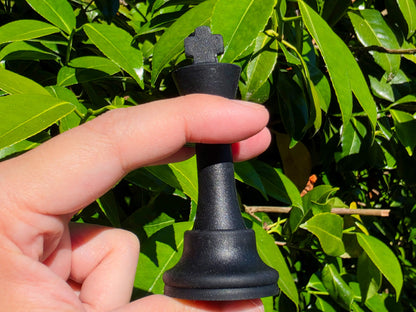 Demonstration of a flexible black silicone chess king piece being squeezed in hand.