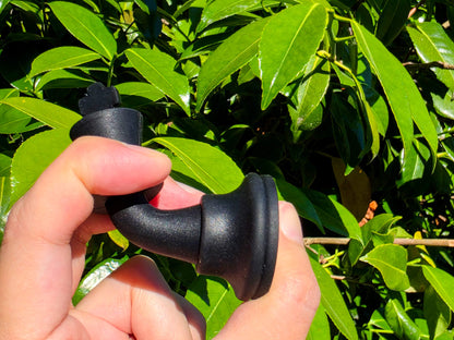 Hand squishing and bending a flexible, durable black silicone chess piece to show elasticity.