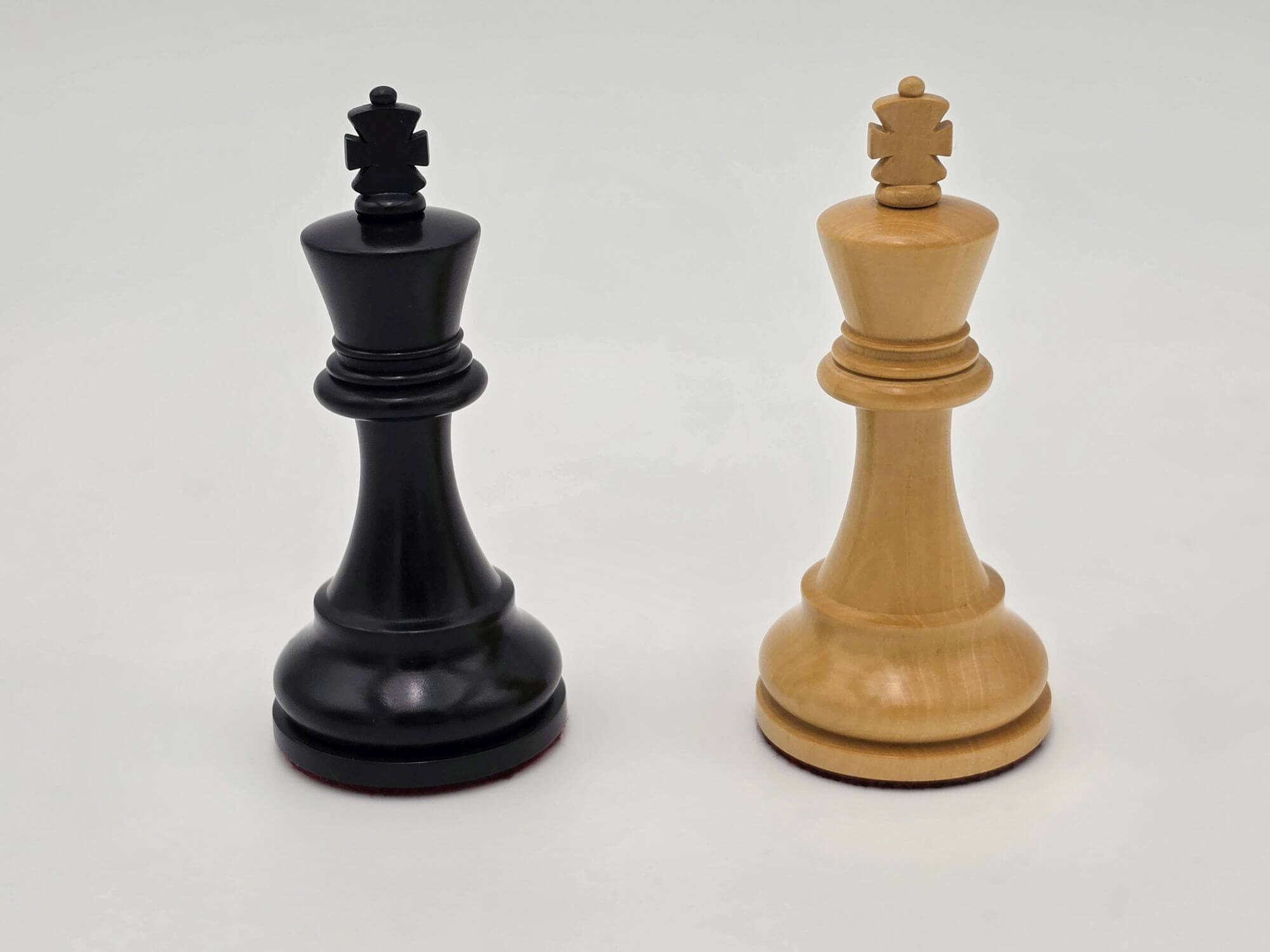 Black and natural wood Judit Polgar chess set kings standing side by side against a white background.