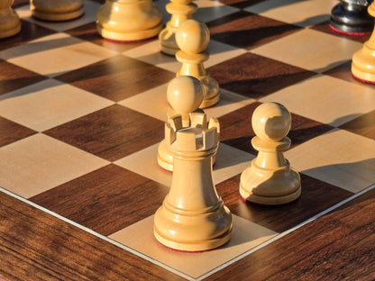 Close-up view of a natural wood rook piece positioned on the corner square of a Judit Polgar chessboard.