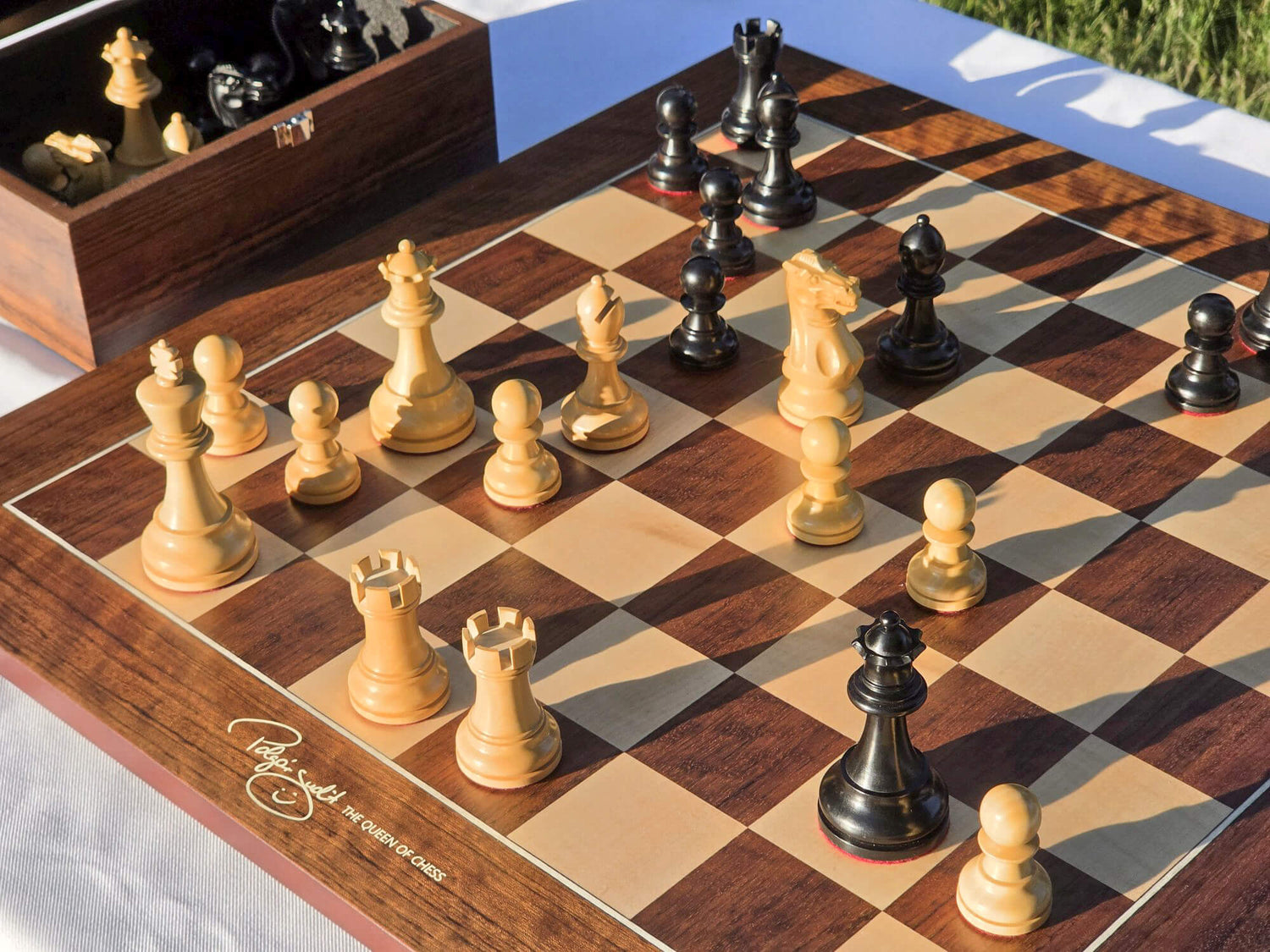 Judit Polgar Queen of Chess signature detail on the corner of the wooden chessboard with pieces in play.