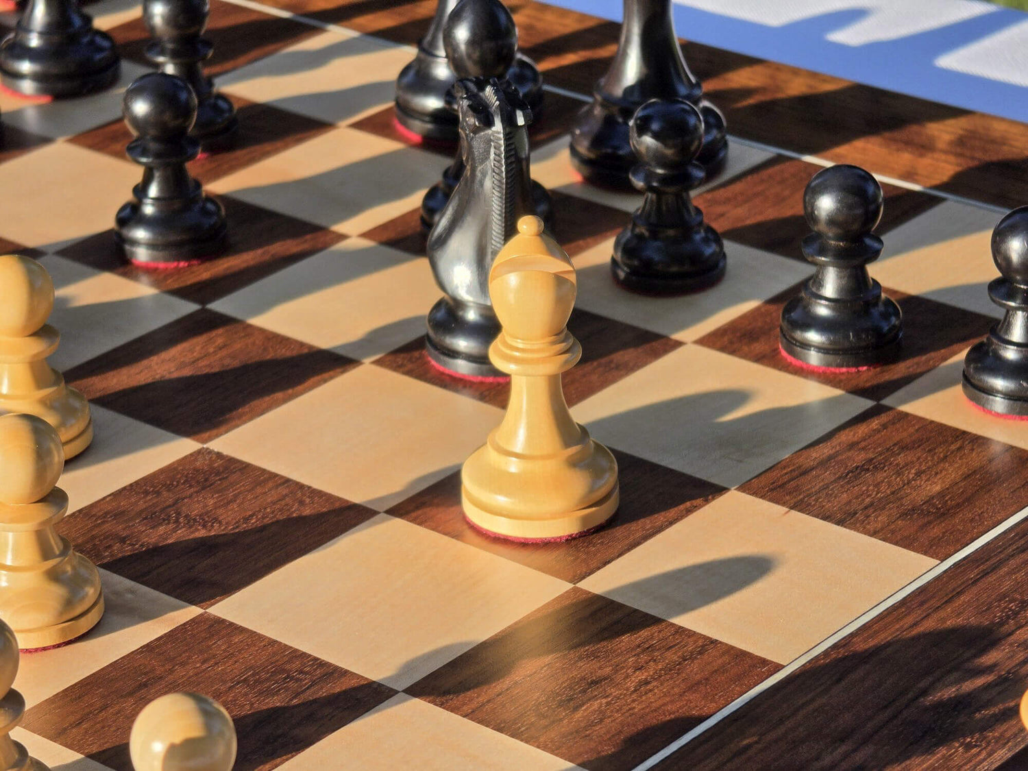 Close-up shot of the white bishop piece on a Judit Polgar wooden chessboard.