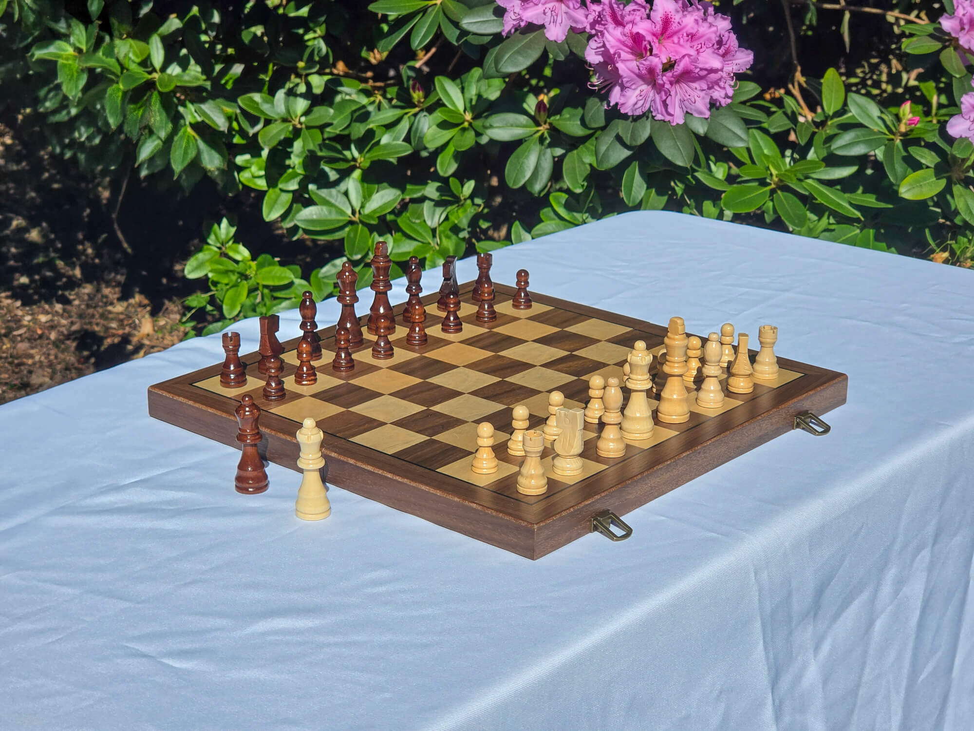 Marquis Magnetic Walnut Wooden Chess Set displayed outdoors on a table with pink flowers
