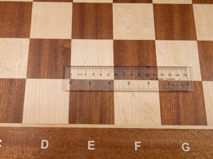 Close-up top view of the Monarch chess board with a transparent ruler placed across a square, confirming the precise 57mm regulation square measurement.