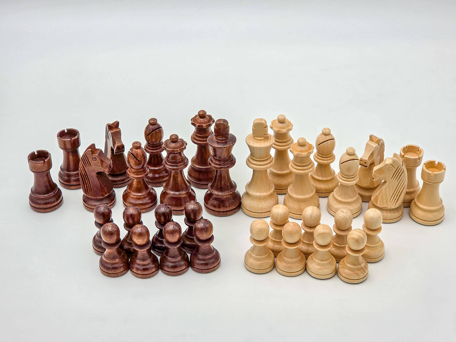 Studio shot showcasing a full 34-piece set of light and dark Germanic-style wooden chess pieces, neatly arranged in a lightbox.