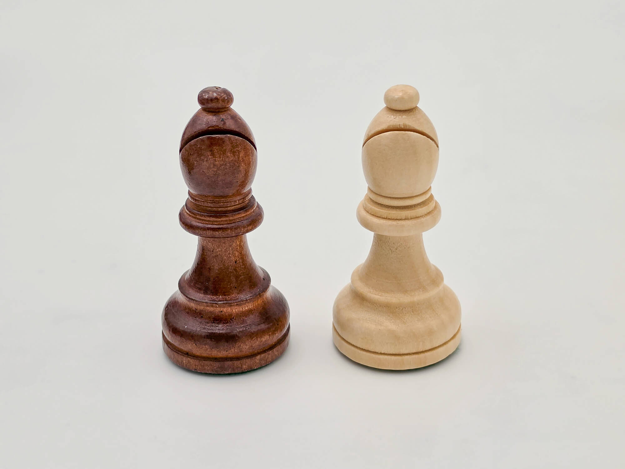 Detailed close-up of the light and dark Germanic-style wooden bishops from the Monarch chess piece collection.