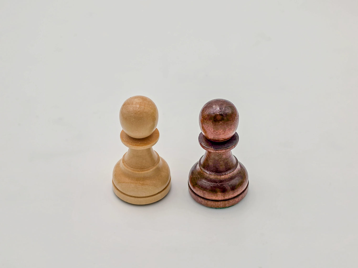 Macro shot of the light and dark Germanic-style wooden chess pawns from the Monarch Series, showing the polished finish and handcrafted wood grain.