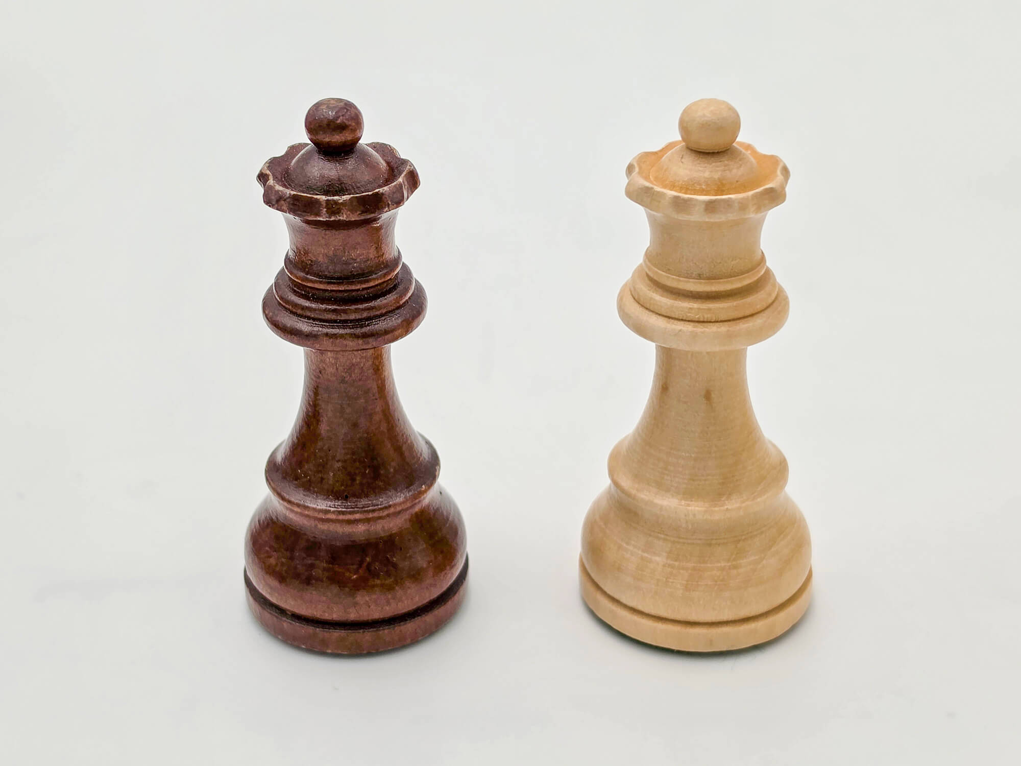 Detailed shot of the light and dark wood Germanic chess queens, part of the Monarch luxury collection.