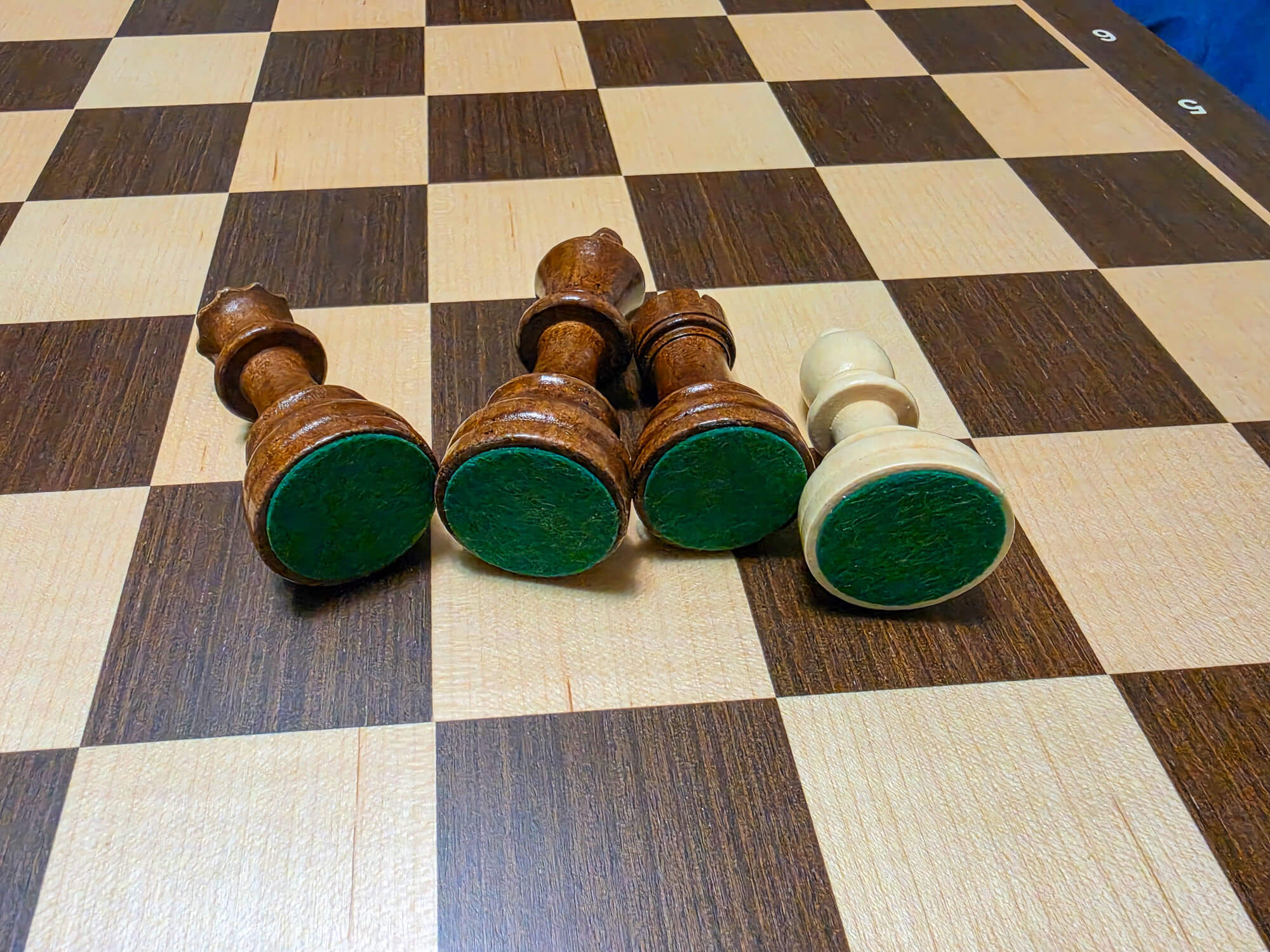 Close-up view showing the high-quality green felt bases on the bottom of Monarch chess pieces.