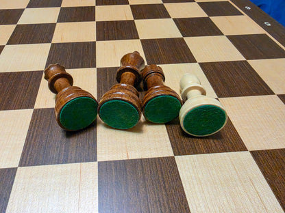 Close-up view showing the high-quality green felt bases on the bottom of Monarch chess pieces.