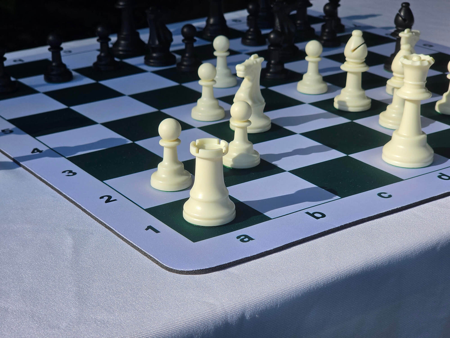 Close-up corner view of a mousepad chess board showing clear algebraic notation coordinates and a white rook piece on the a1 square.