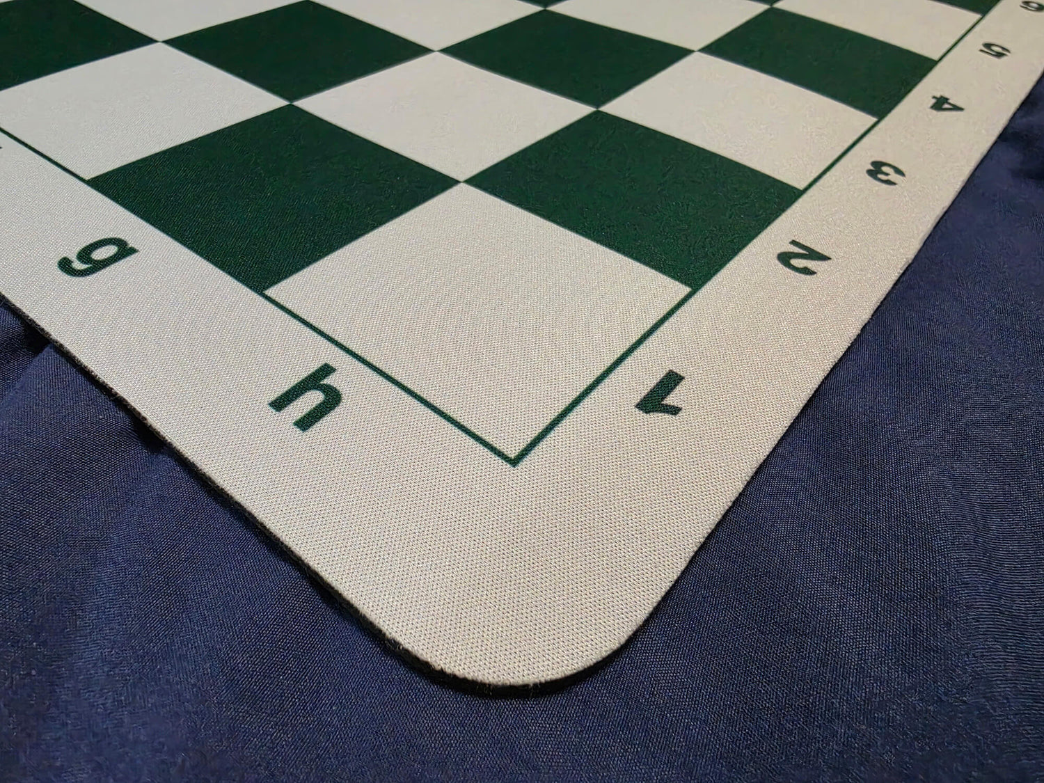 Close-up detail shot of the bottom edge of a green and white mousepad chessboard, clearly displaying the algebraic notation letters and numbers.