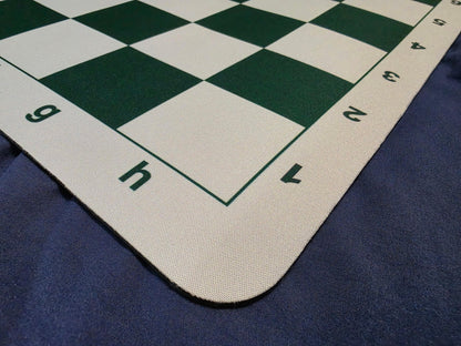 Close-up detail shot of the bottom edge of a green and white mousepad chessboard, clearly displaying the algebraic notation letters and numbers.