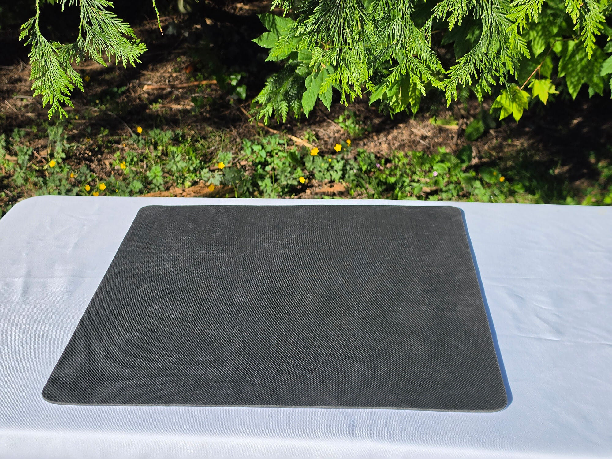 The textured, black non-slip rubber backing of a mousepad chess board displayed flat on a white surface.