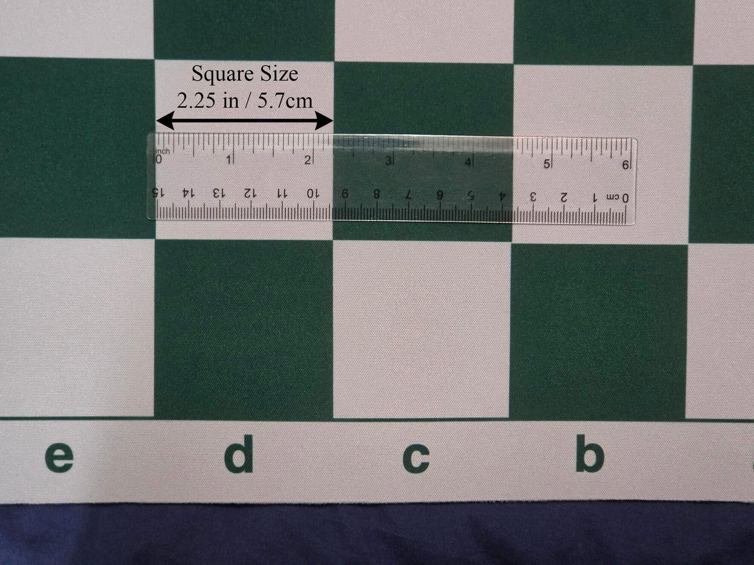 High-definition close-up product photograph of a green and white mousepad chess board section with a transparent ruler and callout labels verifying the 2.25-inch square dimension.