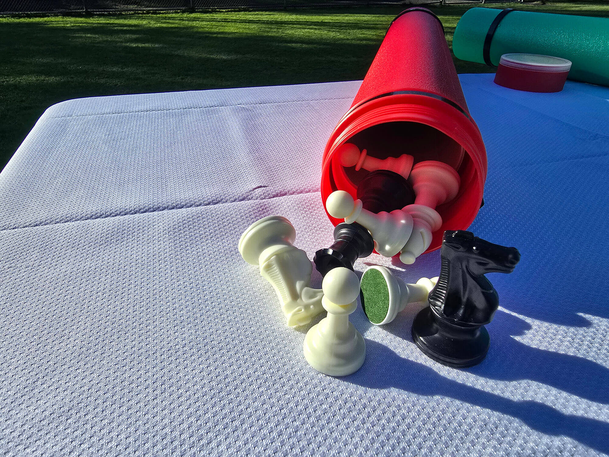 Red Sentry telescopic chess tube with Staunton chess pieces spilling out on a white tablecloth.
