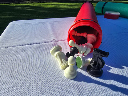 Red Sentry telescopic chess tube with Staunton chess pieces spilling out on a white tablecloth.