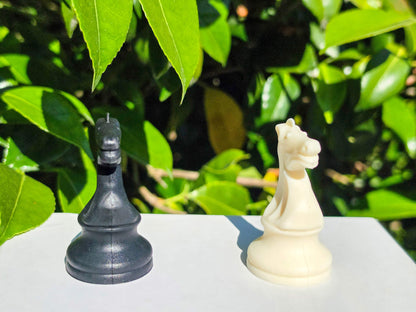 Detailed close-up of black and white silicone chess knight pieces on an outdoor table.
