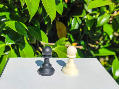 Close-up view of black and white silicone chess pawn pieces outdoors.
